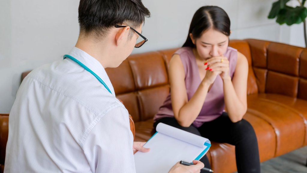 Hidradenitis Suppurativa Is It Contagious? 2 Facts You Should Know a man writing on a clipboard next to a woman who appears to be discussing her condition with a possible hidradenitis suppurativa specialist.