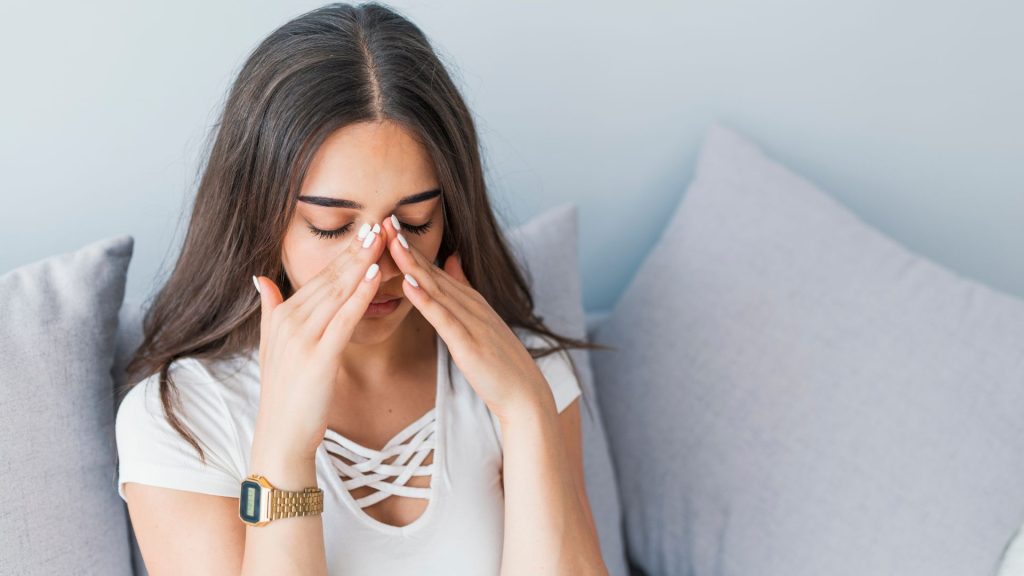 What Is Hs Hidradenitis Suppurativa: An In-Depth Look a woman with her hands on her nose, displaying symptoms of hidradenitis suppurativa.