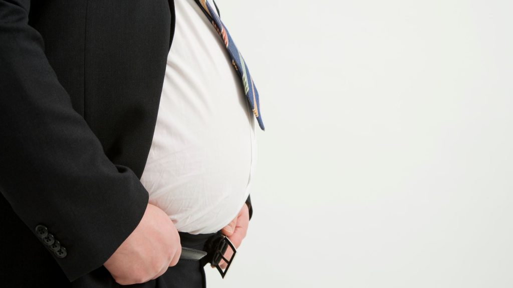 a man in a suit is holding his stomach for comorbidities of hidradenitis suppurativa