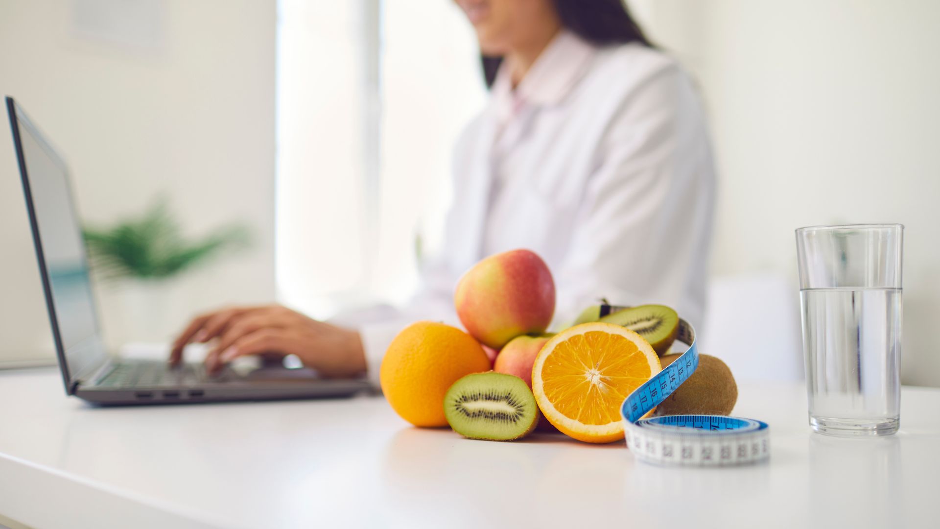 Get lifestyle tips on productivity from a woman sitting at a desk with fruit and a laptop.