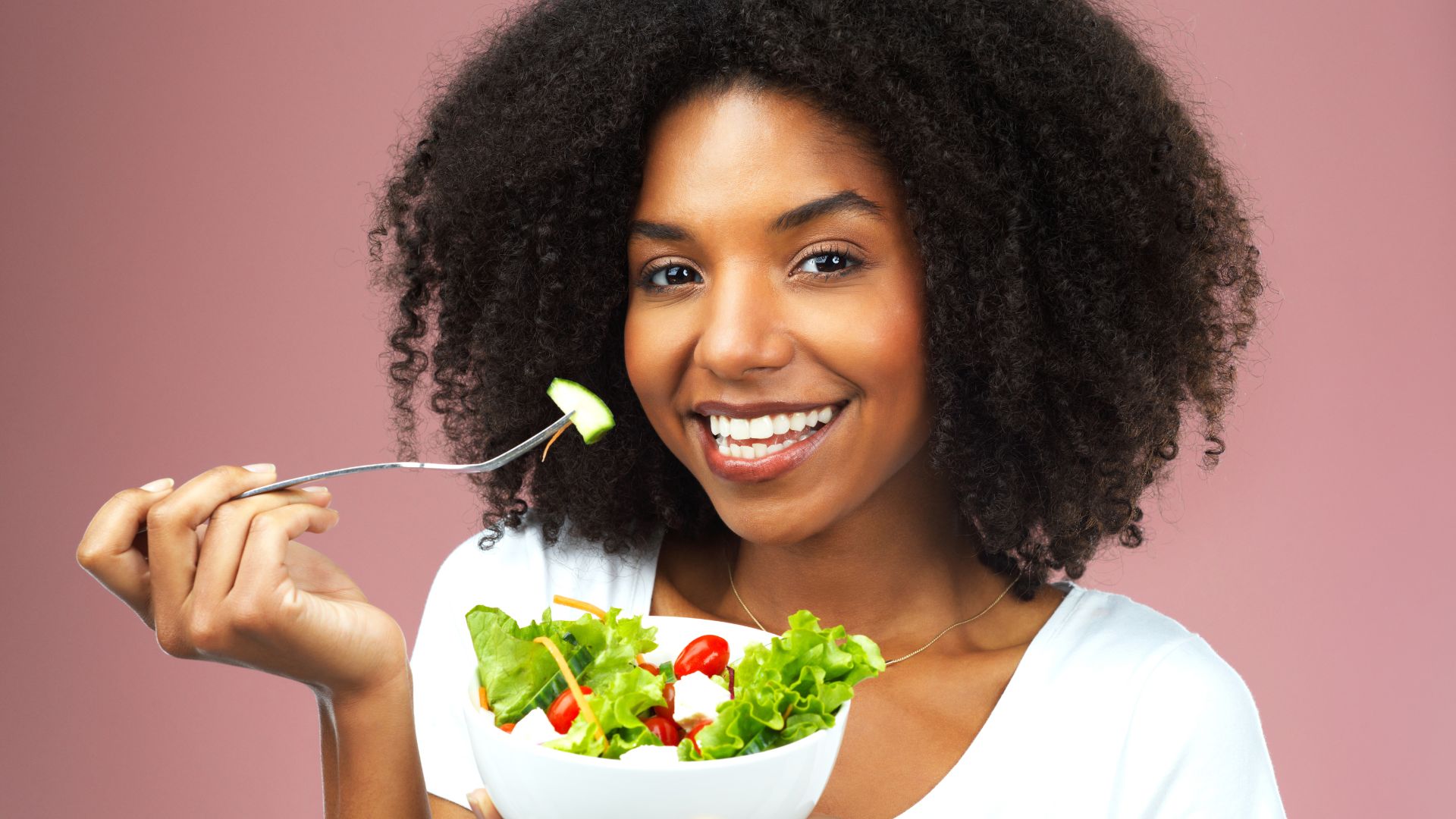 A black woman enjoying a healthy salad with a fork.