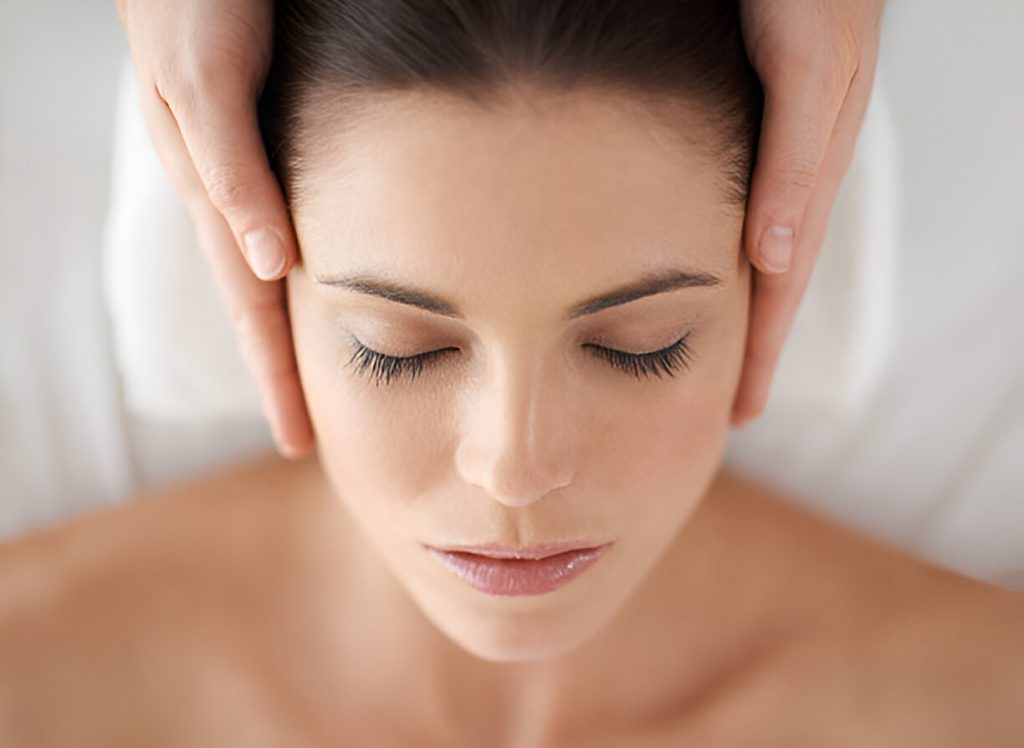 Holistic Approach To Hidradenitis Suppurativa: Exploring Natural Treatments And Complementary Therapies a person with closed eyes receiving a head massage, with hands on both sides of the head, lying down in a relaxed position.